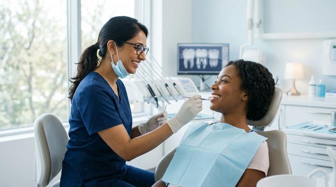 A smiling patient receives a general dentistry checkup from a friendly SameDay Dental professional in a bright, modern clinic.